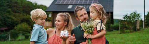 web-close-up-of-young-family-holding-paper-model-of-ho-2022-11-10-01-07-15-utc
